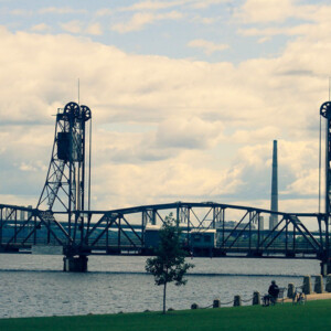 A cyclist stops for a rest on the shore of the St. Croix River with the aerial lift bridge in the background. Photography: Stillwater, MN. A cyclist stops for a rest on the shore of the St. Croix River with the aerial lift bridge in the background.