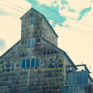 Old grain elevator, built in 1898, rises up against a cloud-filled blue sky. Photography: Stillwater, MN. Old grain elevator, built in 1898, rises up against a cloud-filled blue sky.