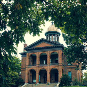 Historic Washington County courthouse framed through the leaves of an oak tree. It was in purposeful operation from 1870 to 1975 and is now open for historic tours and other public functions. Photography: Stillwater, MN. Historic Washington County courthouse framed through the leaves of an oak tree. It was in purposeful operation from 1870 to 1975 and is now open for historic tours and other public functions.