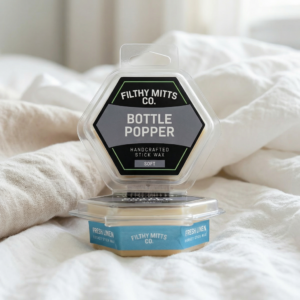Actual photo of product with updated labeling/packaging processed through Kive.ai to generate realistic themed environment product images. Filthy Mitts Co. Bottle Popper Stick Wax